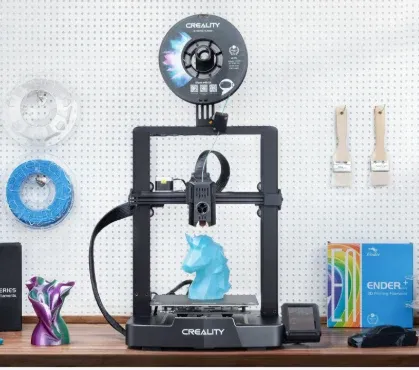 Impressora 3D Creality Ender 3 V3 KE em uma bancada, imprimindo uma peça azul, com o rolo de filamento no topo