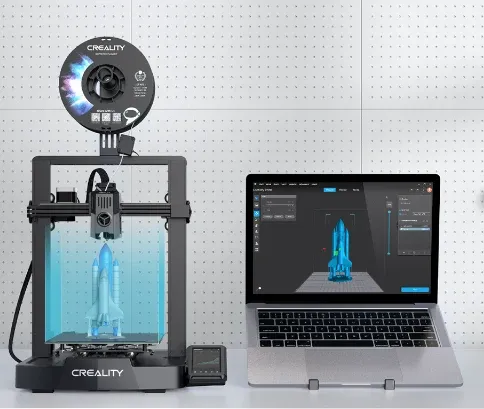 Impressora 3D Creality Ender 3 V3 KE ao lado de um notebook mostrando a peça pronta para imprimir no programa de fatiamento