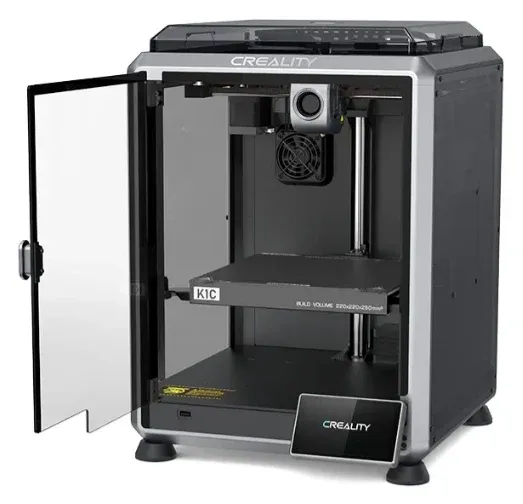 Creality K1C com a porta de vidro aberta, mostrando a chapa PEI, o cabeçote de impressão e o ventilador auxiliar da câmara